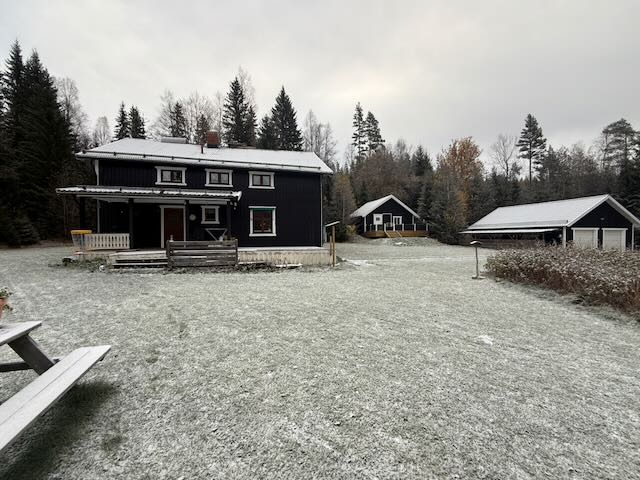The dark wooden house at Flottstad in early winter, with frost on the grass and a smaller building behind it