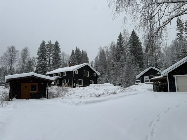 The house and its outbuildings in deep snow, with forest behind